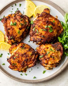 four crab cakes on a plate with lemon wedges and parsley garnish