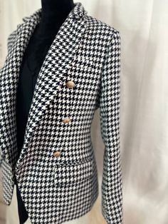 Stay warm in style with this Houndstooth Tweed Blazer. Crafted of heavyweight material, the blazer boasts two pockets and luxe gold buttons. The interior is lined for added comfort and warmth. You'll stay fashionable and cozy all season long. Luxury Houndstooth Outerwear For Fall, Luxury Houndstooth Outerwear For Winter, Luxury Houndstooth Winter Outerwear, Winter Business Tweed Jacket With Houndstooth Pattern, Fall Sport Coat With Houndstooth Pattern And Suit Collar, Winter Houndstooth Blazer With Notch Lapel, Winter Business Houndstooth Tweed Jacket, Classic Double-breasted Houndstooth Blazer, Houndstooth Tweed Jacket With Suit Collar For Work