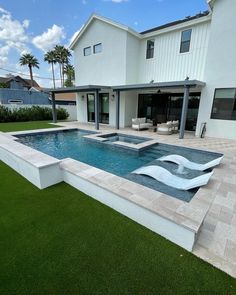 a large swimming pool in the middle of a lawn area next to a white house