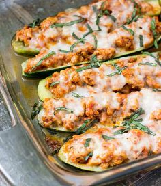 stuffed zucchini boats with meat and cheese in a glass dish on a wooden table