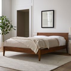 a bed sitting in a bedroom on top of a wooden floor next to a window