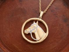 a gold necklace with a horse head on it