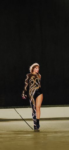 a woman in an animal print outfit is walking with a stick on the floor,