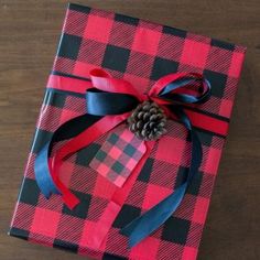 a present wrapped in red and black plaid paper with a pine cone on it's top