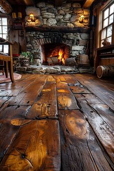 an old log cabin with wood flooring and stone fire place in the fireplace area