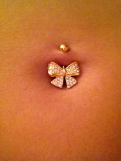 a close up of a person's stomach with a gold bow pin on it