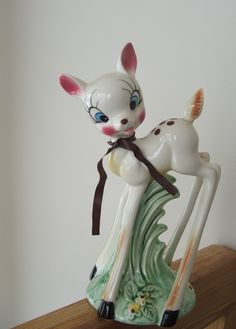 a ceramic deer figurine sitting on top of a wooden shelf next to a wall