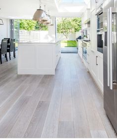 an open kitchen and dining room with skylights above the countertop, along with hardwood flooring