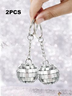 two silver disco ball shaped key chains hanging from each other with the words 2 pcs on them