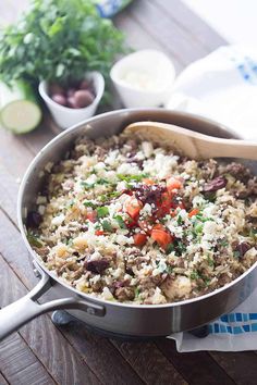 a pan filled with rice and vegetables on top of a wooden table