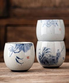 two blue and white vases sitting on top of a wooden table next to each other