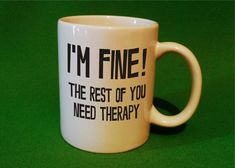 a coffee mug with the words i'm fine on it sitting on a green surface