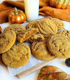 several cookies are arranged on a table next to a glass of milk and pumpkins