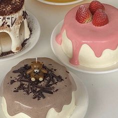 three cakes on white plates with chocolate and strawberries