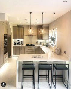 a kitchen with three stools in front of an island and two lights hanging from the ceiling