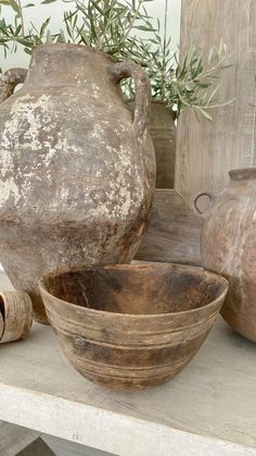 two large vases sitting on top of a table next to bowls and other items