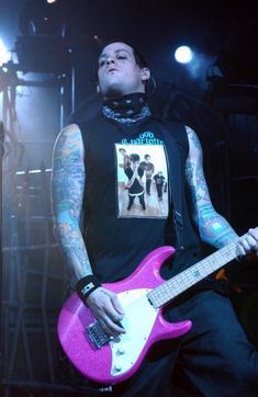 a man holding a pink guitar on stage