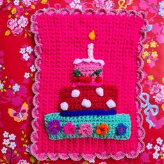 a crocheted birthday cake on a pink blanket