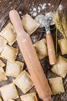 some ravioli and a rolling pin on a wooden table with flour sprinkled around it