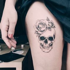 a woman with a skull and roses tattoo on her thigh