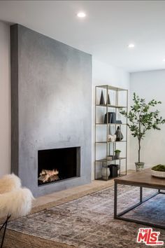 a living room with a fire place in the center and shelves on the wall next to it