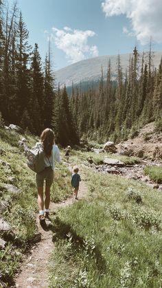 a woman and child walking up a trail in the mountains