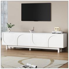 a white entertainment center with a flat screen tv mounted on it's sideboard