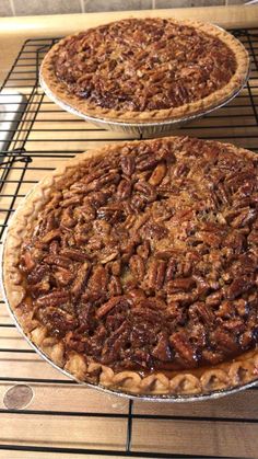 two pecan pies sitting on top of a metal rack in an oven with cooling racks