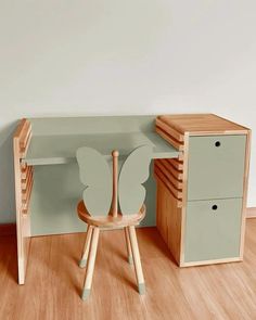 a wooden chair sitting next to a desk with a paper butterfly on top of it