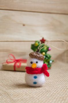 a snowman ornament sitting next to a small christmas tree on a table