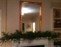 a fireplace with a mirror above it and plants on the mantel in front of it