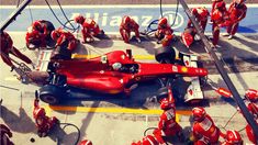 a red race car is parked on the track with other people in red suits around it