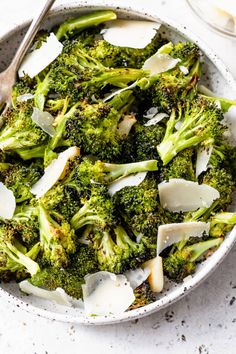 a bowl filled with broccoli and cheese on top of a white tablecloth