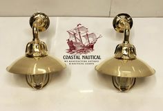 two brass colored wall lights on a white counter top next to a sign that says coastal nautical