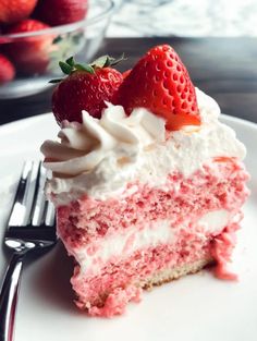 a slice of strawberry cake with whipped cream and strawberries on the top is ready to be eaten