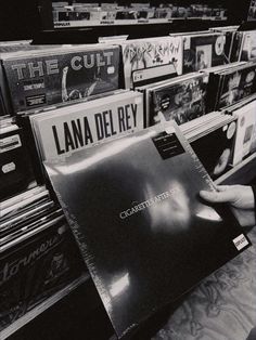 a person is holding up a record in front of a rack of cds and other records