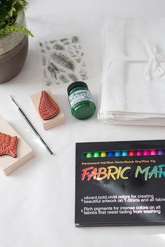 some crafting supplies are laying out on a white tablecloth and next to it is a rubber stamp with the words fabric mart