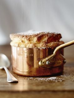 powdered sugar is sprinkled on top of a copper pot with a spoon