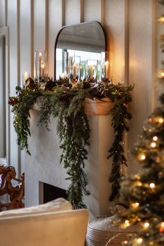 a fireplace decorated for christmas with greenery and candles