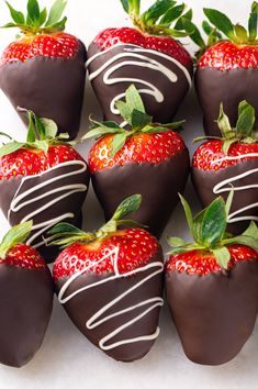 chocolate covered strawberries are arranged on a white surface