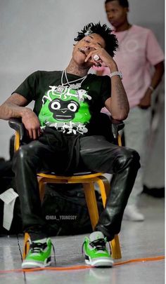 a man sitting in a chair with headphones on his ears and wearing a green t - shirt