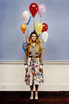 a woman standing in front of a wall with balloons