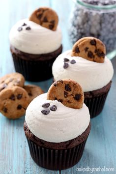 chocolate cupcakes with white frosting and cookies on top, sitting on a blue table