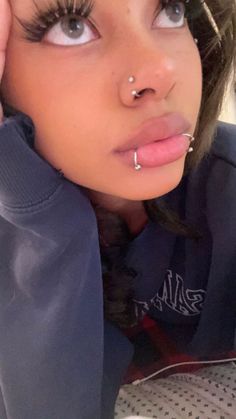 a close up of a person with piercings on her nose and wearing a hoodie