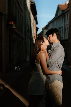 a man and woman standing next to each other in the middle of an alleyway