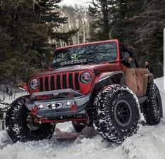 a red jeep is driving through the snow