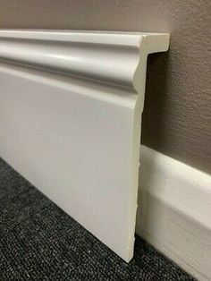 an image of a white wall paneling in the corner of a room with carpeted floor