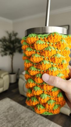 a person is holding a cup holder made out of crocheted yarn