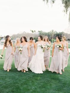 a group of bridesmaids walking in the grass