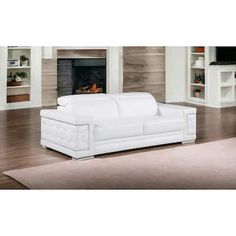 a white leather couch sitting in front of a fire place on top of a hard wood floor